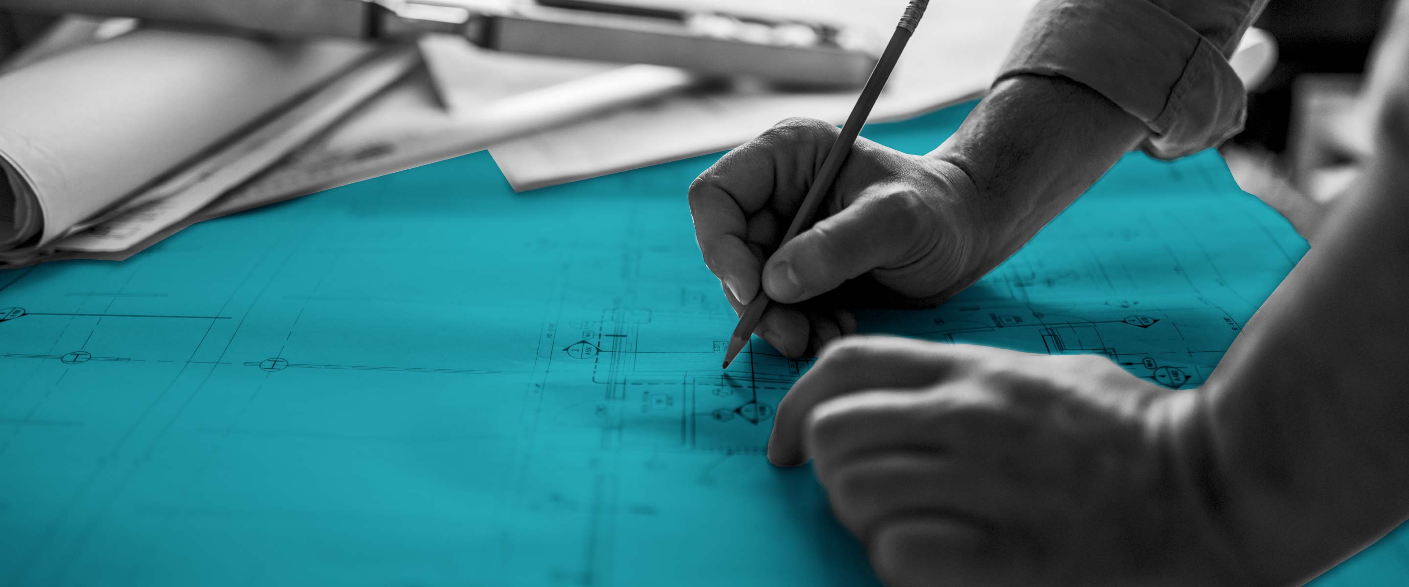 Schwarz-Weiß-Nahaufnahme von händischen Planungsarbeiten. Große Blaupause in petrol hervorgehoben
