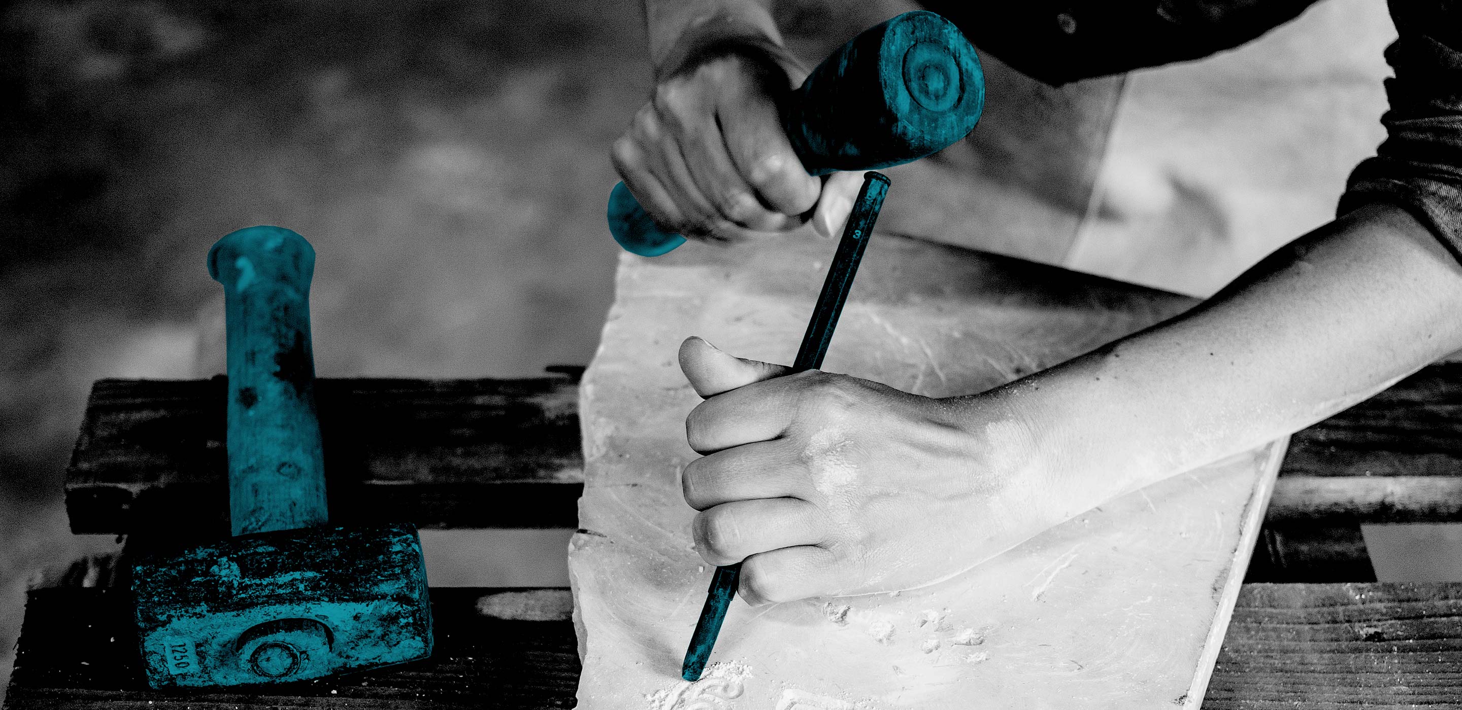 Schwarz-Weiß-Nahaufnahme von Arbeiten an Steinplatte. Hammer und Meißel in petrol hervorgehoben