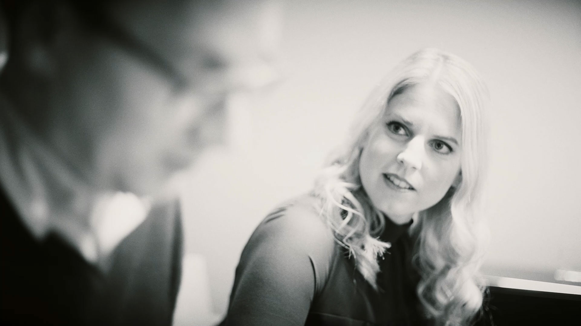 Schwarz-Weiß-Aufnahme Elena Reuter im Gespräch mit Person im Vordergrund, die verschwommen dargestellt ist